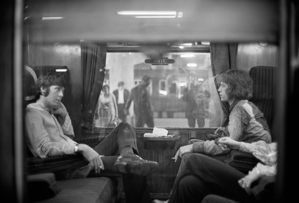 Paul McCartney of The Beatles and Mick Jagger of The Rolling Stones sit opposite each other on a train at Euston Station in 1967 (Getty)