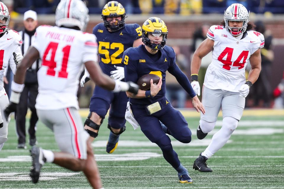 Michigan quarterback J.J. McCarthy runs past Ohio State defensive end JT Tuimoloau (44) during the second half at Michigan Stadium in Ann Arbor on Saturday, Nov. 25, 2023.