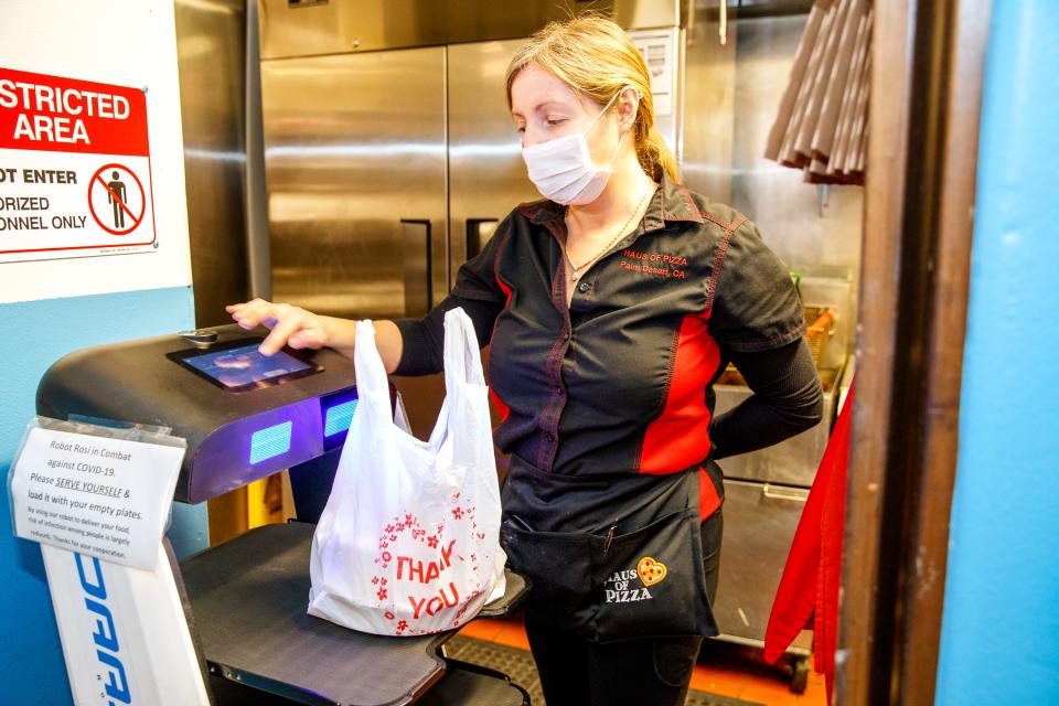 Haus of Pizza owner Iryna Pyle inputs the table number for her serving robot, Robot Rosi, to deliver food inside the restaurant in Palm Desert, Calif., on Jan. 10, 2022. After having difficulty finding workers despite raising wages, Haus of Pizza took the innovative step of leasing a serving robot as a worker replacement and combat against COVID-19. 