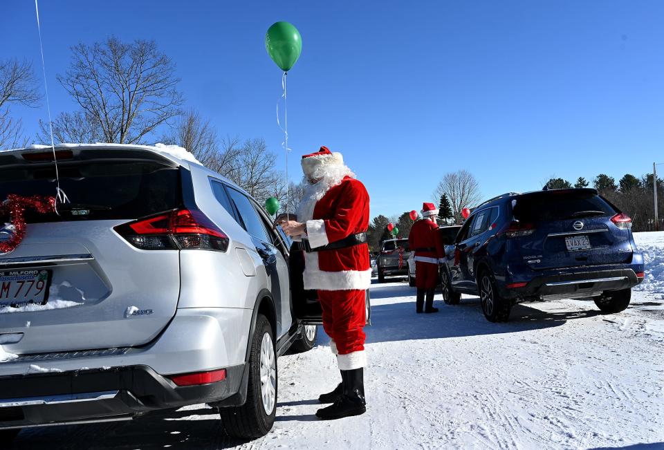 Santa Claus ties balloons to a car at the Pinecrest Golf Club prior to the Holliston Lions Club Santa Caravan through Holliston neighborhoods, Saturday Dec. 19, 2020.  Caravans carrying Santa Claus and an elf delivered goodie bags and a socially distanced photo with Santa to 160 families in town.  