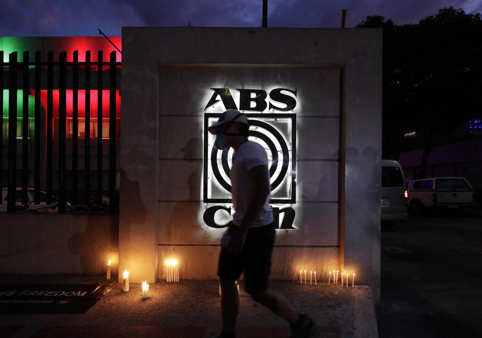 A man wearing a mask walks pasta makeshift memorial outside the headquarters of broadcast network ABS-CBN on Tuesday, May 5, 2020 in Manila, Philippines. A government agency has ordered the country's leading broadcast network, which the president has targeted for its critical news coverage, to halt operations. (AP Photo/Aaron Favila)