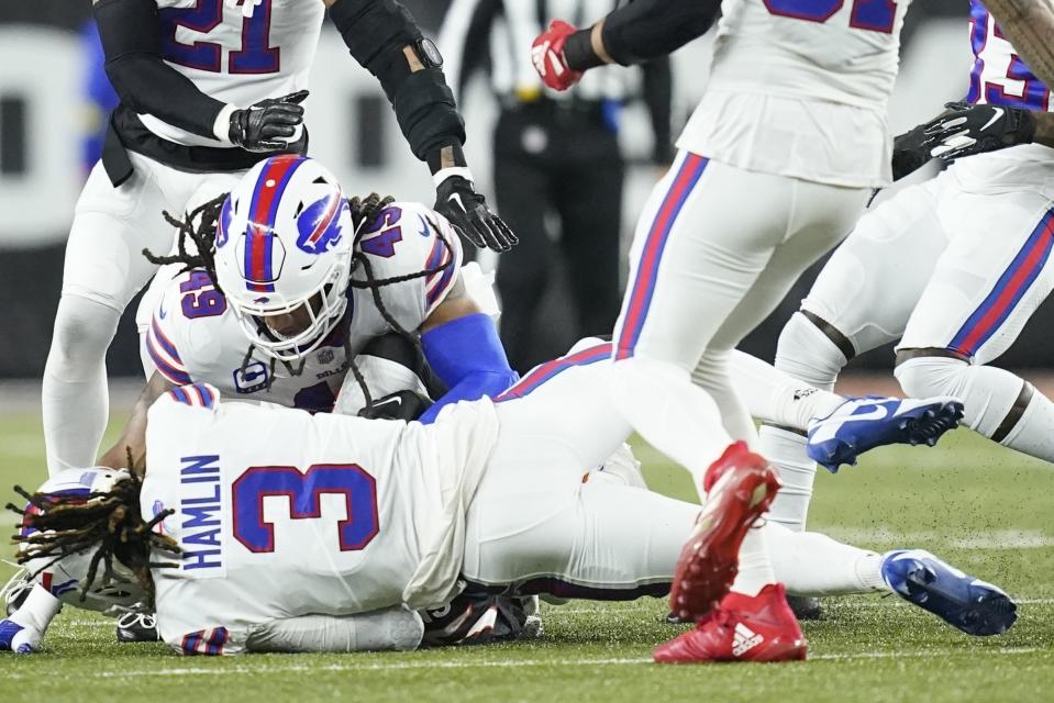CLARIFIES THAT IMAGE SHOWN IS FROM THE END OF A TACKLE SECONDS BEFORE HAMLIN COLLAPSED - Buffalo Bills safety Damar Hamlin (3) lies on the turf after making a tackle on Cincinnati Bengals wide receiver Tee Higgins, who is blocked from view, as Buffalo Bills linebacker Tremaine Edmunds (49) assists at the end of the play during the first half of an NFL football game between the Cincinnati Bengals and the Buffalo Bills, Monday, Jan. 2, 2023, in Cincinnati. After getting up from the play, Hamlin collapsed and was administered CPR on the field. (AP Photo/Joshua A. Bickel)