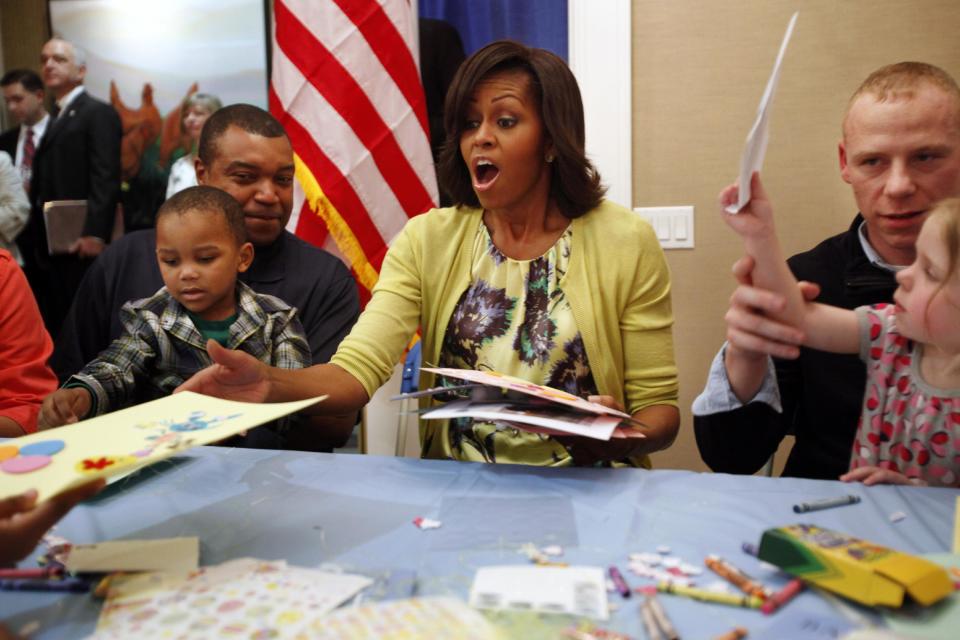 First lady Michelle Obama reacts on receiving multiple Easter cards from families at Fisher House, including Eun White, 3, sitting on his father Army Major Eunotchol White, left, and Madison Tharp, 3, seated with her father Army Staff Sgt. Randy Tharp, right, at Walter Reed National Military Medical Center in Bethesda, Md., Wednesday, April 4, 2012. The Fisher House program houses military families while a family member is receiving medical care. (AP Photo/Jacquelyn Martin)