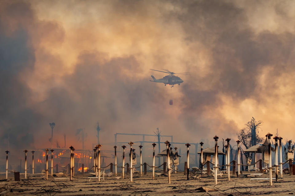 A helicopter flies above a fire at Le Capannine beach in Catania, Sicily, Italy on July 30.<span class="copyright">Roberto Viglianisi—Reuters</span>