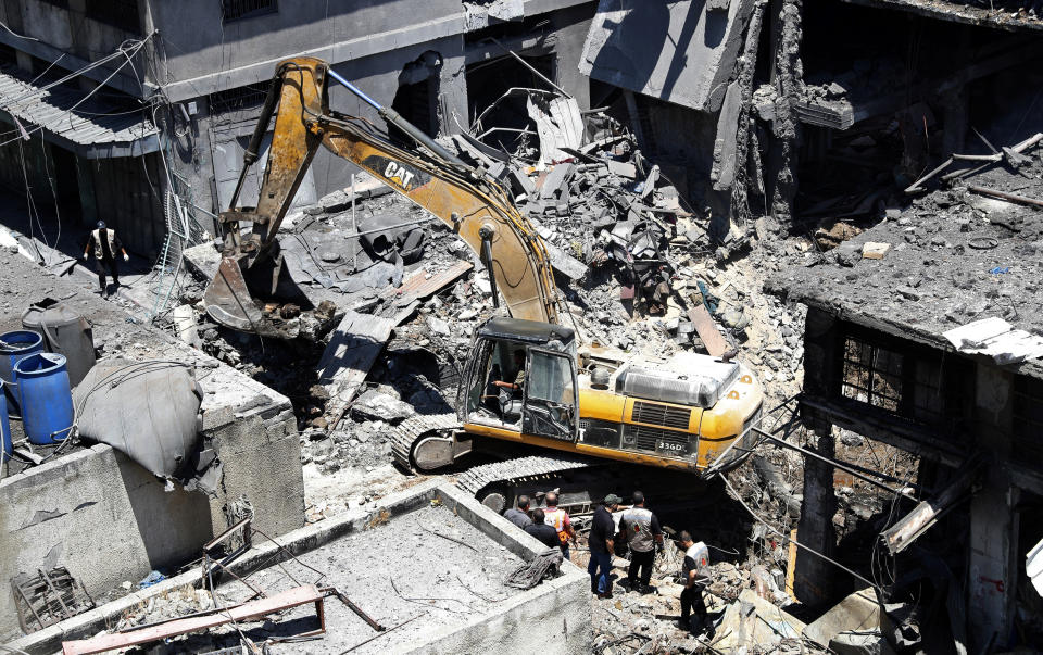 Palestinian rescuers and security personnel inspect the site of an explosion as a mechanical digger works to remove rubble, in Gaza City, Gaza, Thursday, July 22, 2021. At least one person was killed and 10 injured Thursday when an explosion tore through a house in a popular market, the interior ministry said. (AP Photo/Adel Hana)