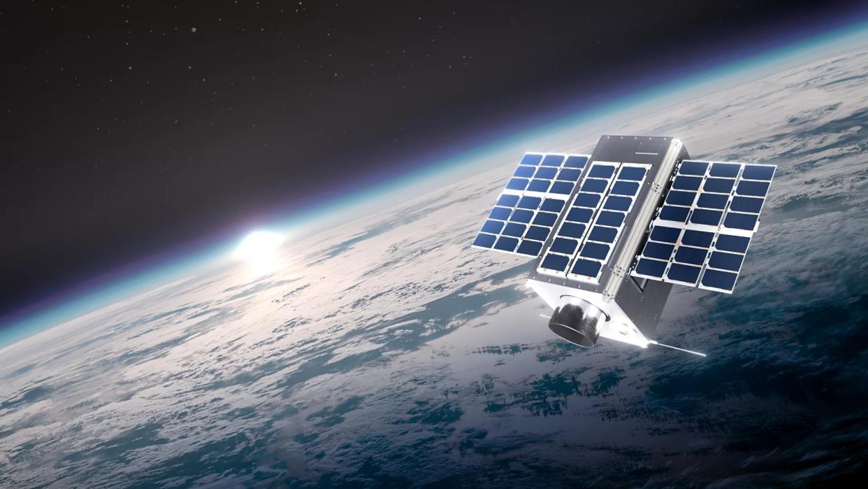  A rectangular satellite covered in solar panels floats in space above Earth. 