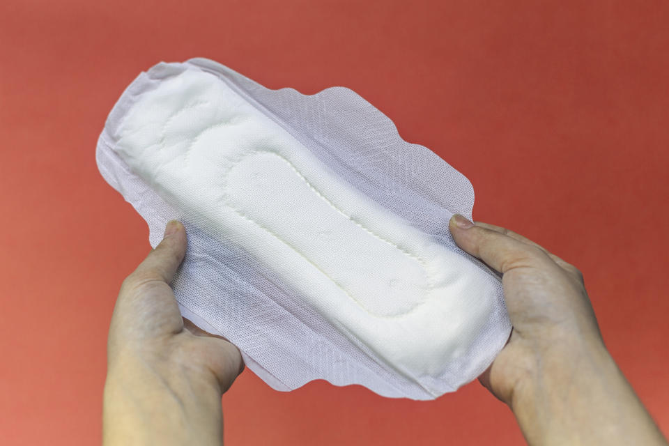 Woman&#39;s hands holding two feminine hygiene pads. Hands of female hold menstrual pads or sanitary napkins for women on pink background