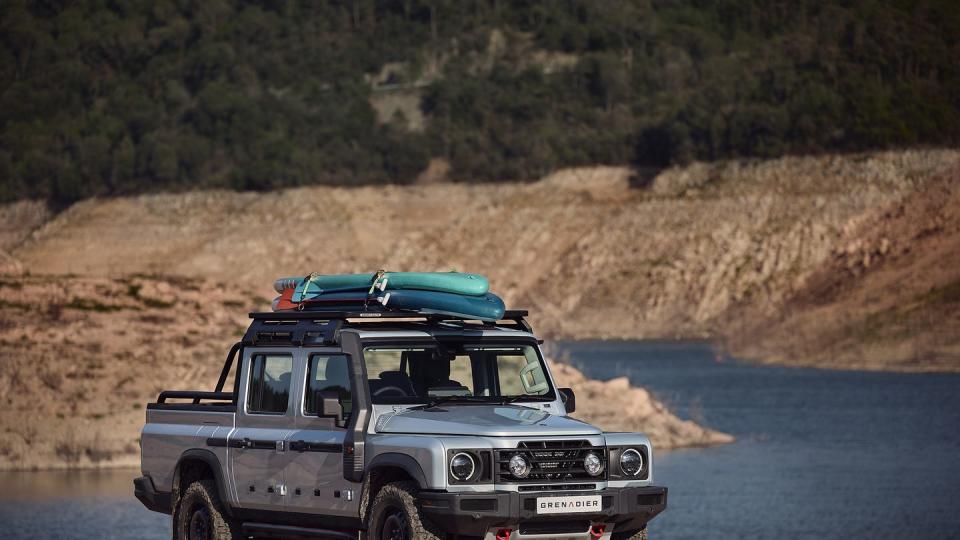 a silver four door truck with two boards on the roof sits in front of a flooded canyon