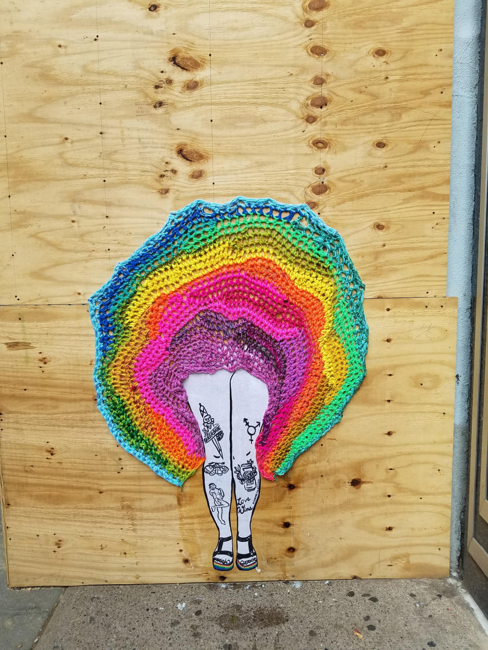 This May 2019 photo provided by Nicole Nikolich shows a collaborative street art installation between Nikolich and Symmone Salib, a painter and street artist, on a wooden wall in Center City, Philadelphia, Pa. This piece was created to celebrate Philly pride month. Knitters and crocheters call it yarn bombing. They're using fiber arts to make political statements, or maybe just to lift people's spirits. Experts say yarn bombing is part of a long tradition in which women use textile arts to agitate, excite or inspire. (Nicole Nikolich/Lace In The Moon via AP)