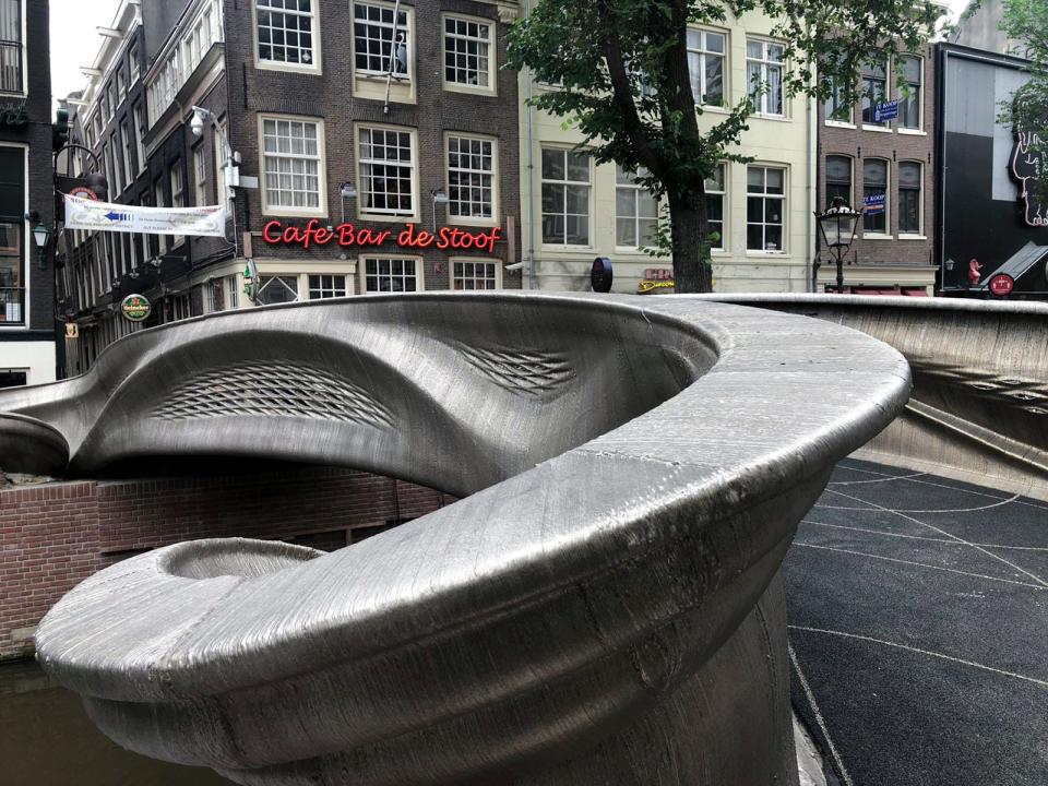 A steel 3D-printed pedestrian bridge spans a canal in the heart of the red light district in Amsterdam, Netherlands, Thursday, July 15, 2021. The distinctive flowing lines of the 12-meter (40-foot) bridge were created using a 3D printing technique called wire and arc additive manufacturing that combines robotics with welding. (AP Photo/Aleksandar Furtula)