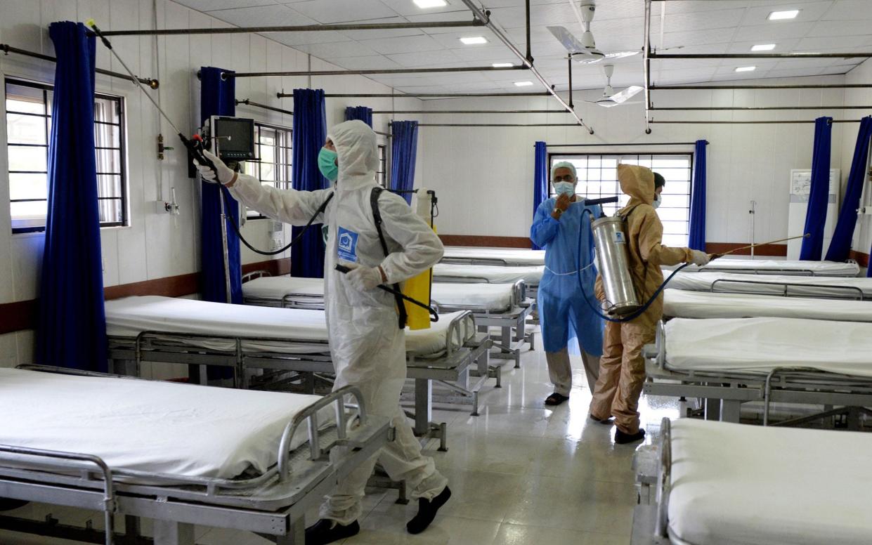 Pakistani workers spray disinfectant at PIMS hospital in Islamabad, Pakistan - SOHAIL SHAHZAD/EPA-EFE/Shutterstock