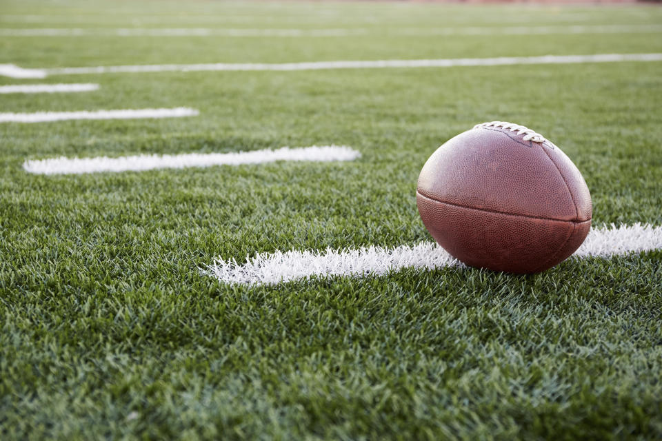 Close up of American football ball on green playing field