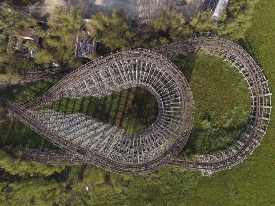 In this June 22, 2019 aerial photo, a roller coaster and concession buildings of the abandoned Six Flags Great Adventure Amusement Park are seen in New Orleans. The abandoned New Orleans amusement park that has stood empty since Hurricane Katrina in 2005 may finally be torn down. The Six Flags park never reopened after the levees failed and flooded the city with water. Mayor LaToya Cantrell says her office is targeting the site for demolition. (DroneBase via AP)