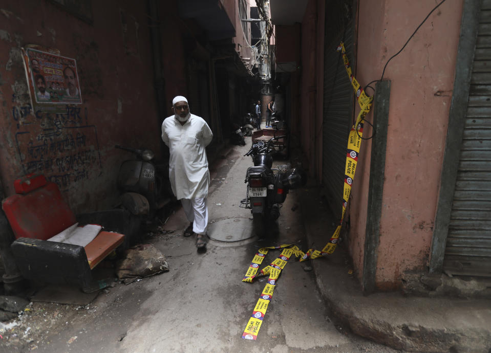 A elderly Muslim man walks by an ill-fated building which caught fire on Sunday in New Delhi, India, Monday, Dec. 9, 2019. Authorities say an electrical short circuit appears to have caused a devastating fire that killed dozens of people in a crowded market area in central New Delhi. Firefighters fought the blaze from 100 yards away because it broke out in one of the area's many alleyways, tangled in electrical wire and too narrow for vehicles to access. (AP Photo/Manish Swarup)