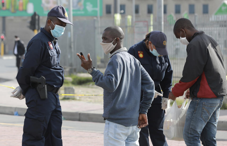 Police check permits at a taxi rank in Bellville a suburb of Cape Town, South Africa, Thursday, May 21, 2020, during an eased lockdown in the country to prevent the spread of COVID-19. With dramatically increased community transmissions, Cape Town has become the centre of the coronavirus outbreak in South Africa and the entire continent. (AP Photo/Nardus Engelbrecht)