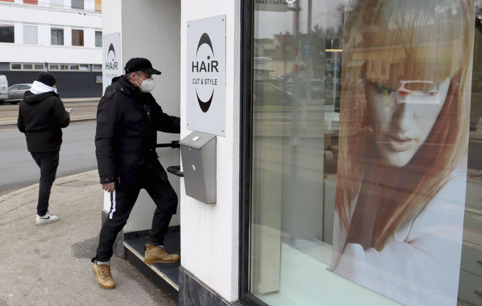 A man in a mask goes to a reopened hairdresser after lock down in Vienna, Austria, Monday, Feb. 8, 2021. The Austrian government has moved to restrict freedom of movement for people, in an effort to slow the onset of the COVID-19 coronavirus. (AP Photo/Ronald Zak)