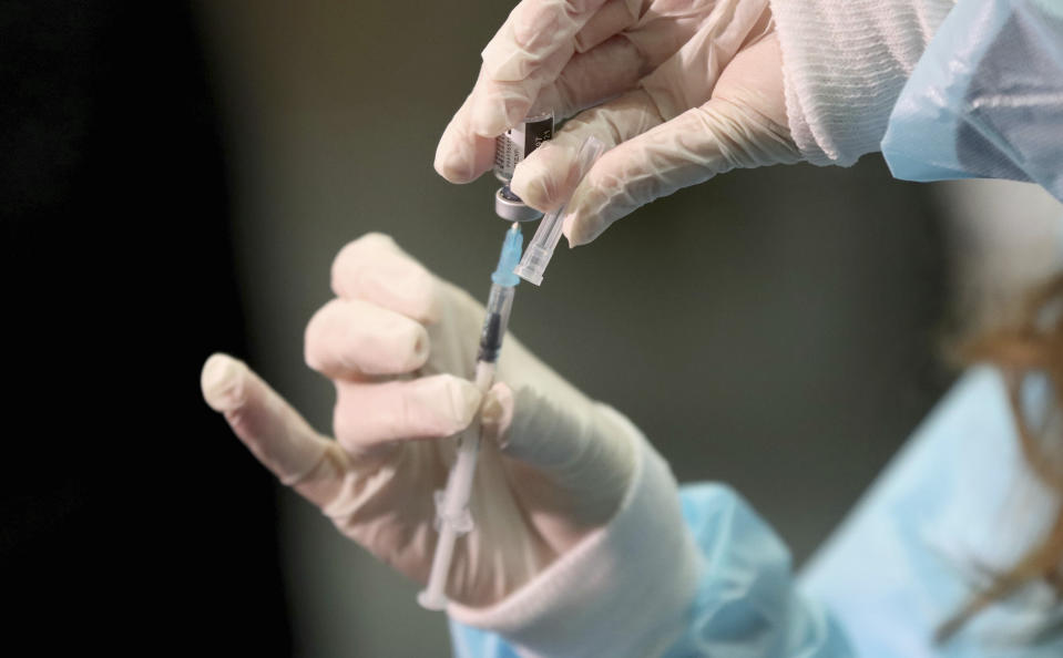 A medical worker holding a Pfizer-BioNTech vaccine and a syringe during mass vaccination starts in Vienna, Austria, Friday, Jan. 15, 2021. Authorities started to vaccinate the most vulnerable people in a coordinated effort. (AP Photo/Ronald Zak)