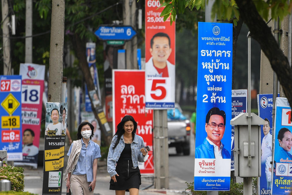People walk past electoral campaign posters in Bangkok.