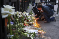 Woman light candles near the Vladislav Ribnikar school in Belgrade, Serbia, Wednesday, May 3, 2023. A 13-year-old who opened fire Wednesday at his school in Serbia's capital drew sketches of classrooms and made a list of people he intended to target in a meticulously planned attack, police said. He killed eight fellow students and a guard before calling the police and being arrested. (AP Photo/Armin Durgut)