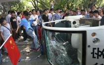 A Chinese demonstrator kicks a broken police vehicle during a protest against Japan in Shenzhen, China Sunday, Sept. 16, 2012. Protesters in China began another day of demonstrations against Japan, after protests over disputed islands spread across numerous cities and at times turned violent. (AP Photo/Apple Daily) HONG KONG OUT, TAIWAN OUT, NO SALES