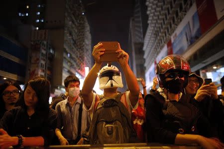 A pro-democracy protester wearing a helmet takes a picture of riot police with his mobile phone at the Mongkok shopping district of Hong Kong October 19, 2014. REUTERS/Carlos Barria