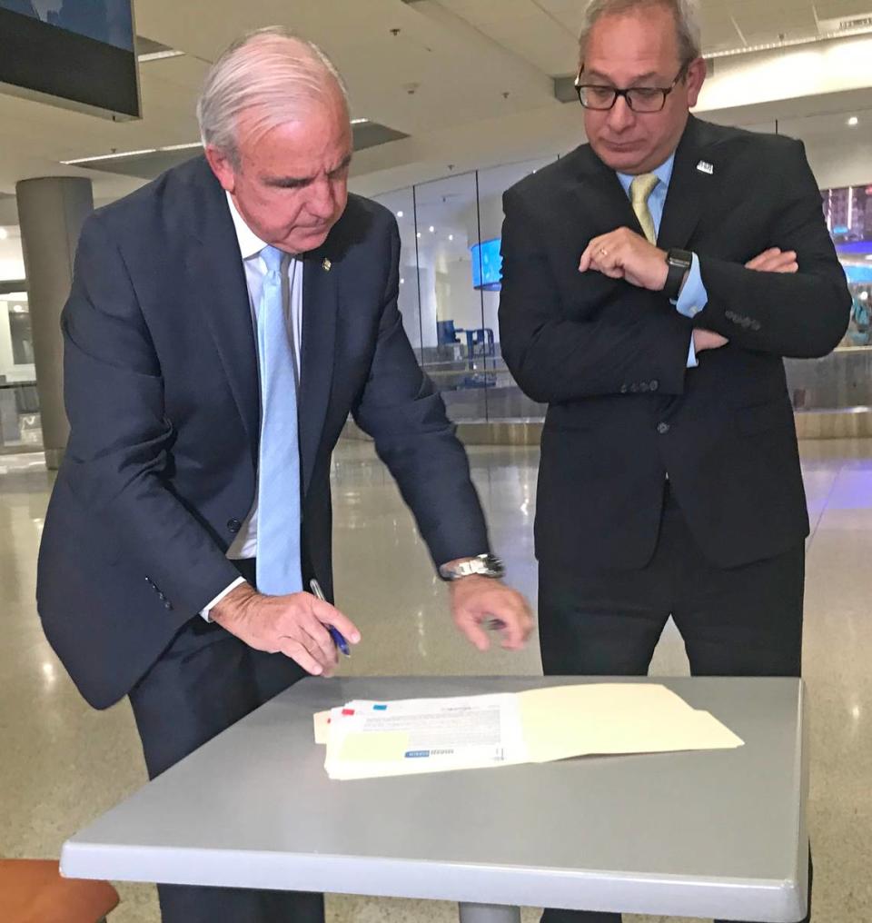 After landing at Miami International Airport Wednesday night from a White House meeting with cruise executives, Miami-Dade Mayor Carlos Gimenez signed an emergency declaration over the coronavirus pandemic. Next to him is airport director Lester Sola