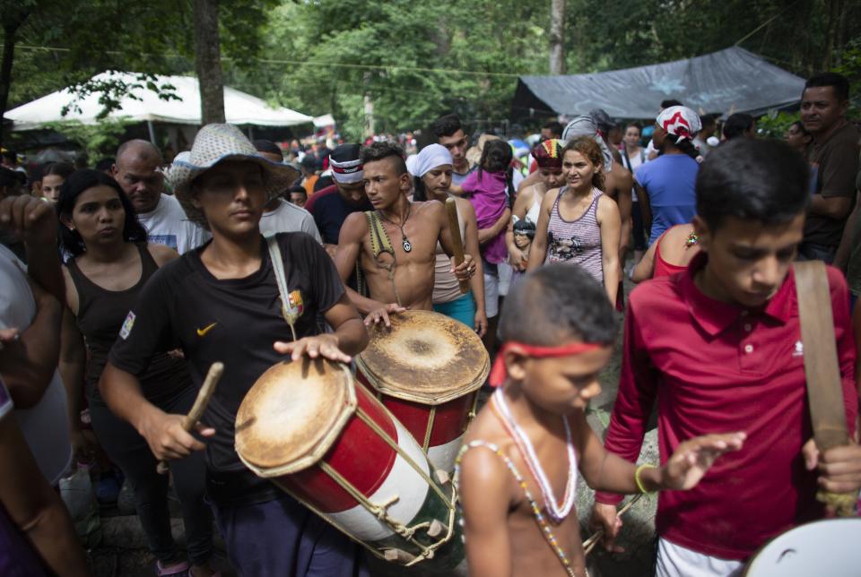 In this photo taken Oct 12, 2019, people play drums during a procession on Sorte Mountain where followers of indigenous goddess Maria Lionza gather annually in Venezuela's Yaracuy state. The gathering in honor of Maria Lionza is hundreds of years old and draws on Catholicism, Afro-Caribbean religion Santeria and indigenous rituals, all set to a pulse of constant drumming. (AP Photo/Ariana Cubillos)