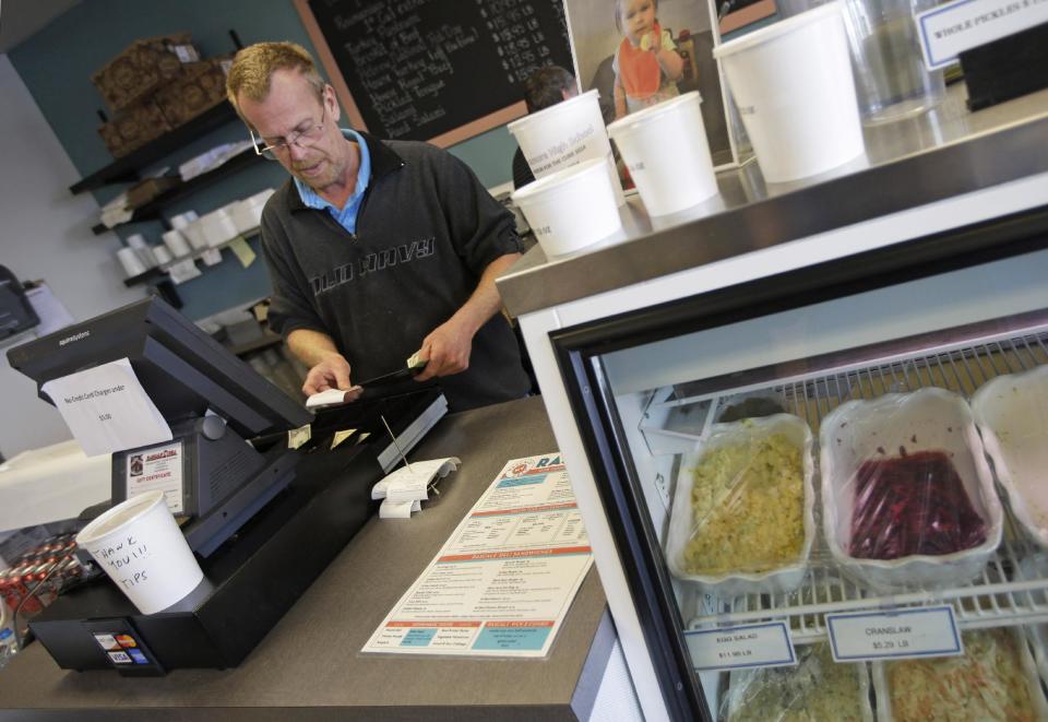 In this Tuesday, Jan. 28, 2014 photo, manager Randy Smith checks the register at Rascal's NY Deli in Cincinnati. Smith says overall business is down at the deli, because of the cold weather, but that their carryout and delivery business is up. (AP Photo)