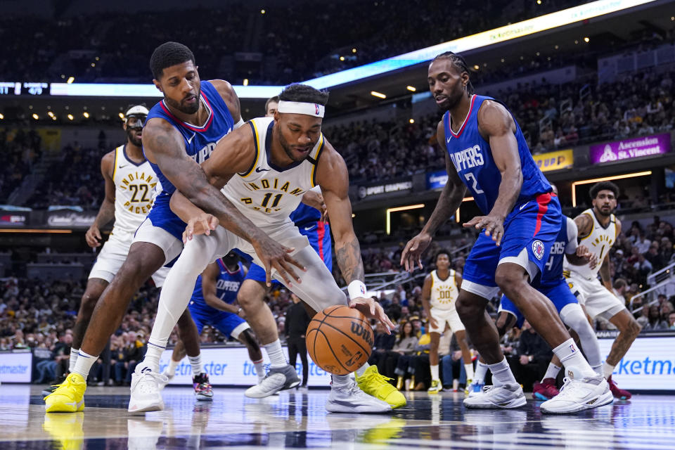 Los Angeles Clippers forward Paul George, left, defends Indiana Pacers forward Bruce Brown (11) during the first half of an NBA basketball game in Indianapolis, Monday, Dec. 18, 2023. (AP Photo/Michael Conroy)