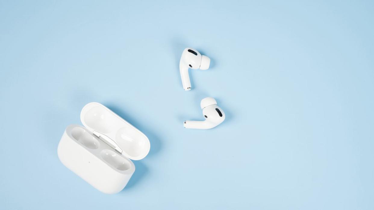 a pair of airpods and case against a blue background