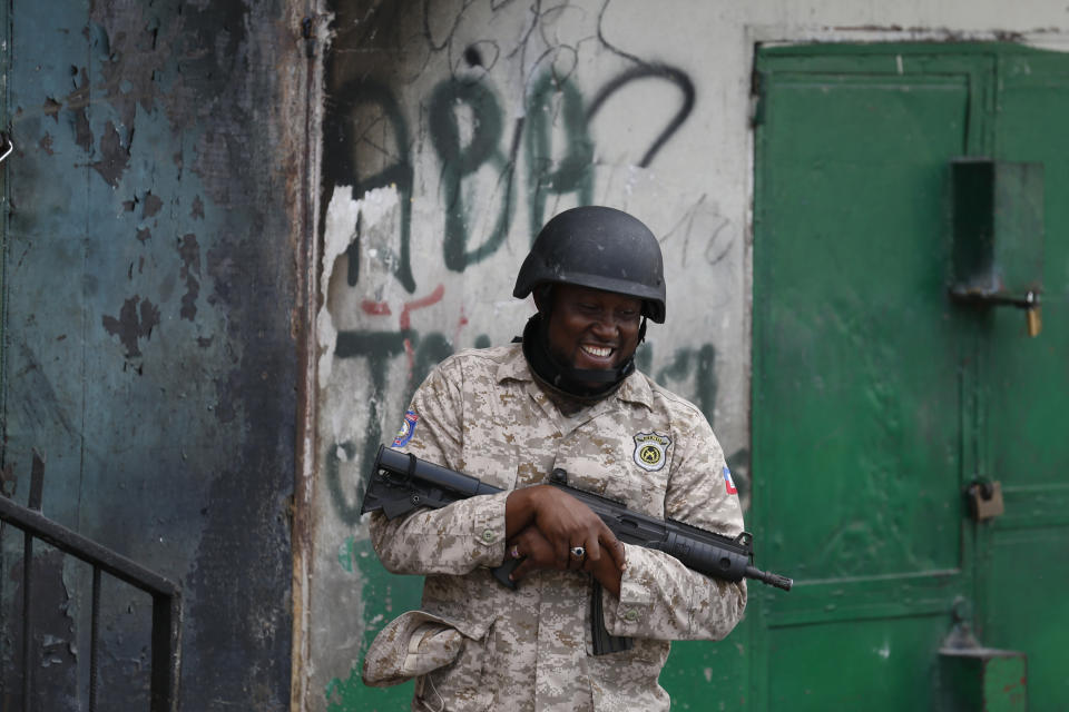 A police officer stands in front of graffiti reading "Down with Jovenel," as police provide security along the route of a march calling for the resignation of President Jovenel Moïse, in Delmas, Port-au-Prince, Haiti, Sunday, Oct. 13, 2019. Thousands of Haitians joined a largely peaceful protest called by the art community Sunday to demand Moïse resign, increasing pressure on the embattled leader after nearly a month of marches that have shuttered schools and businesses.(AP Photo/Rebecca Blackwell)