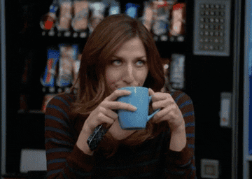 a woman drinking a cup of coffee and rolling her eyes