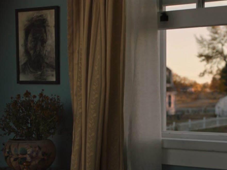 a shot of an open window, curtains drifitng in the breeze, in the last of us. to the left is a sketched painting of nick offerman as bill in the show