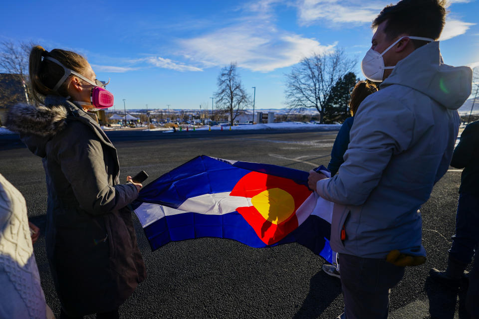 Kelsey Taylor and brother Jeff Alexander hold a Colorado flag while waiting for President Joe Biden's motorcade to pass by during his tour of the Marshall Fire destruction Friday, Jan. 7, 2022, in Louisville, Colo. Taylor and Alexander lost their childhood home in the fire. (AP Photo/Jack Dempsey)