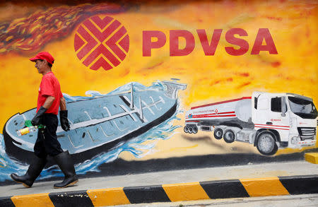 FILE PHOTO: A worker walks past a mural with a PDVSA logo at its gas station in Caracas, Venezuela August 29, 2014. REUTERS/Carlos Garcia Rawlins/File Photo