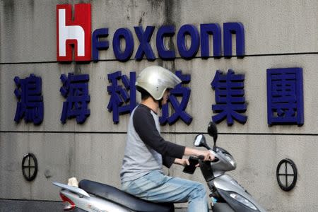 A motorcyclist rides past the logo of Foxconn, the trading name of Hon Hai Precision Industry, in Taipei, Taiwan March 30, 2018. REUTERS/Tyrone Siu/Files