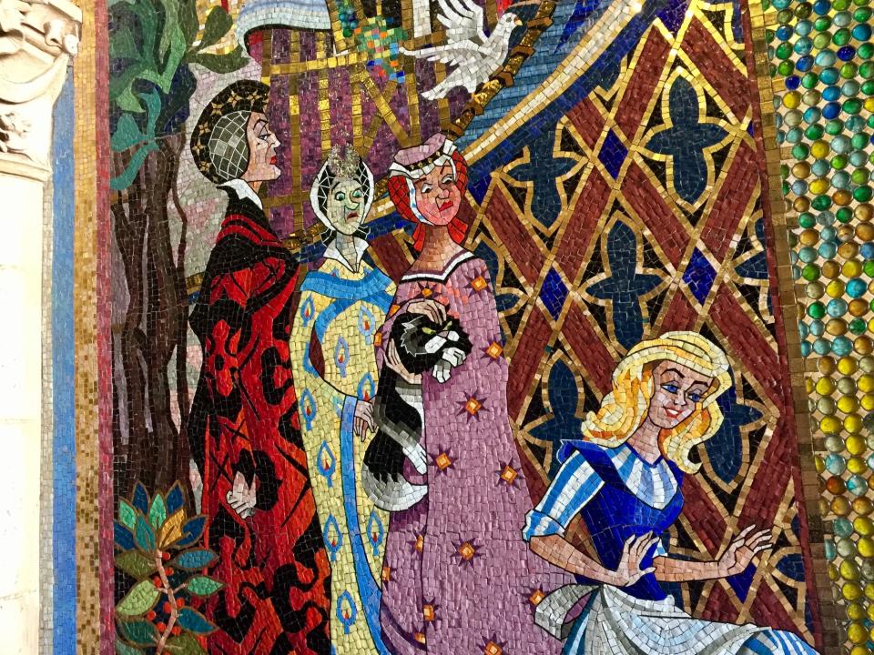 mosaic art piece of cinderella, the evil stepmother, and the evil stepsisters on a wall at disney world