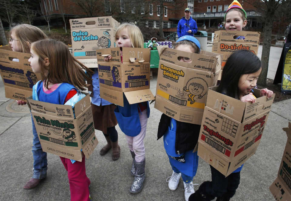 FILE - In a Feb. 18, 2013 file photo dressed in boxes emptied from earlier cookie sales, Girl Scouts from Troop 20337 in Eugene fan out on the University of Oregon campus near the Erb Memorial Union in Eugene, Ore., in search of customers for their cookies. Just a year after its 2012 centennial celebrations, the Girl Scouts of the USA's interconnected problems include declining membership and revenues, a dearth of volunteers, rifts between leadership and grass-roots members, a pension plan with a $347 million deficit, and an uproar over efforts by many local councils to sell venerable summer camps. (AP Photo/The Register-Guard, Chris Pietsch)