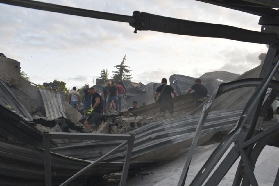 In this photo provided by the National Police of Ukraine, people clear the rubble on the roof of a restaurant RIA Pizza destroyed by a Russian attack in Kramatorsk, Ukraine, Tuesday, June 27, 2023. (National Police of Ukraine via AP)