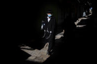 An ultra-Orthodox Jewish man wears protective face masks following government measures to help stop the spread of the coronavirus, as he walk in Jerusalem's Old City, Thursday, July 16, 2020. (AP Photo/Oded Balilty)