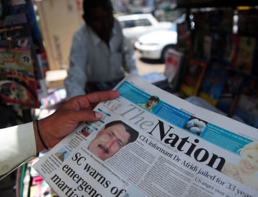 A man reads a newspaper bearing the photograph of Pakistani surgeon Shakeel Afridi, recruited by the CIA to help find Osama bin Laden, at a newsstand in Karachi. Angry US lawmakers Thursday threatened to freeze millions of dollars in vital aid to Islamabad after a Pakistani doctor who helped hunt down Osama bin Laden was jailed for 33 years