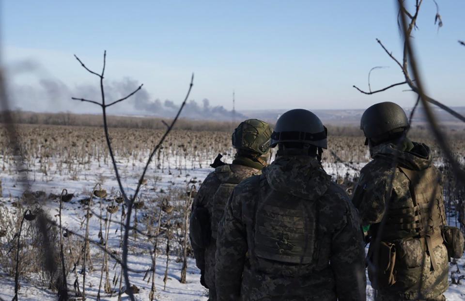 Ukrainian soldiers watch as smoke billows during fighting between Ukrainian and Russian forces in Soledar, Donetsk (AP)