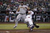 San Francisco Giants' Darin Ruf, left, scores a run on a ball hit by LaMonte Wade Jr. in the first inning during a baseball game against the Arizona Diamondbacks, Monday, July 4, 2022, in Phoenix. (AP Photo/Rick Scuteri)