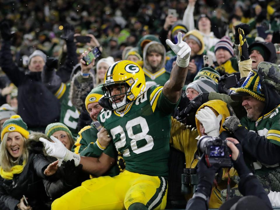 AJ Dillon leaps into the stands after scoring a touchdown against the Seattle Seahawks.