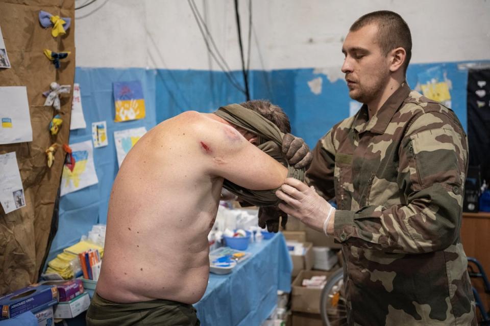 Volodymyr assists a wounded soldier (Reuters)