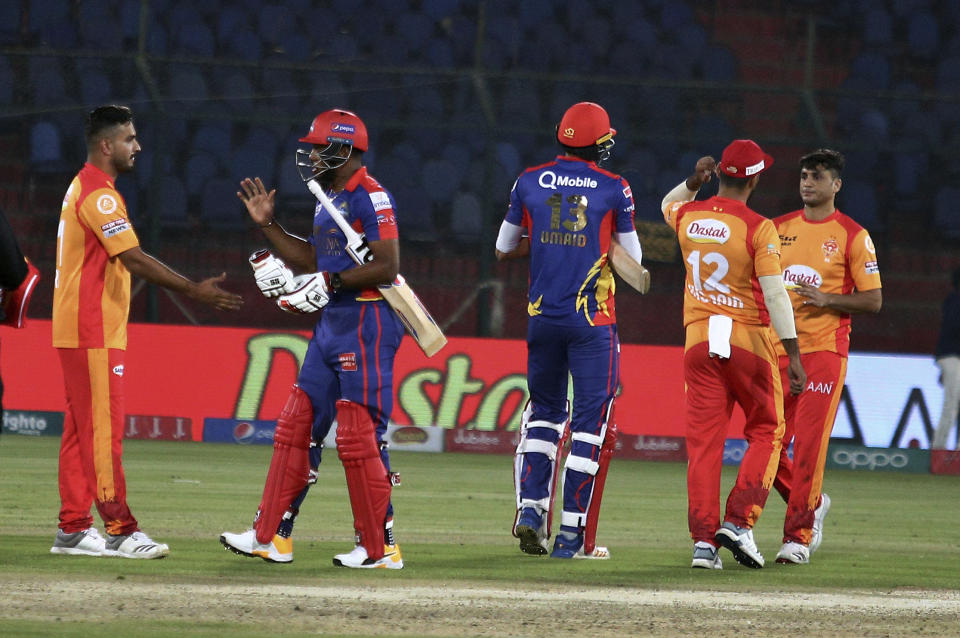 Karachi Kings players Umaid Asif, center, and Chris Jordan, second left, shake hand with Islamabad United players on the end of their Pakistan Super League T20 cricket match at the National Stadium in Karachi, Pakistan, Saturday, March 14, 2020. (AP Photo/Fareed Khan)