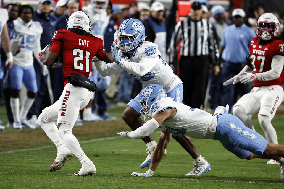 North Carolina State's Jalen Coit (21) is tackled by North Carolina's D.J. Jones (26) and Will Hardy (31) during the first half of an NCAA college football game in Raleigh, N.C., Saturday, Nov. 25, 2023. (AP Photo/Karl B DeBlaker)