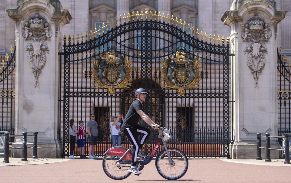 A man rides a city bike outside Buckingham Palace, as people enjoy the good weather in London, Sunday May 31, 2020. The public are being reminded to practice social distancing following the relaxation of coronavirus lockdown restrictions in England. (Dominic Lipinski/PA via AP)