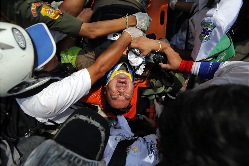 An injured reporter is taken to an ambulance during clashes between the police and anti-government protesters near the Government House in Bangkok