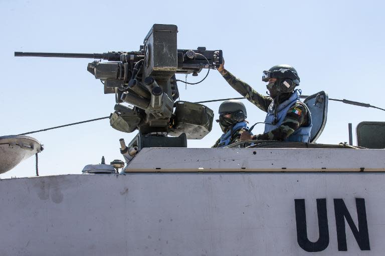 Members of the United Nations Disengagement Observer Force (UNDOF) sit on their armoured vehicles in the Israeli-annexed Golan Heights as they wait to cross into the Syrian-controlled territory, on August 28, 2014
